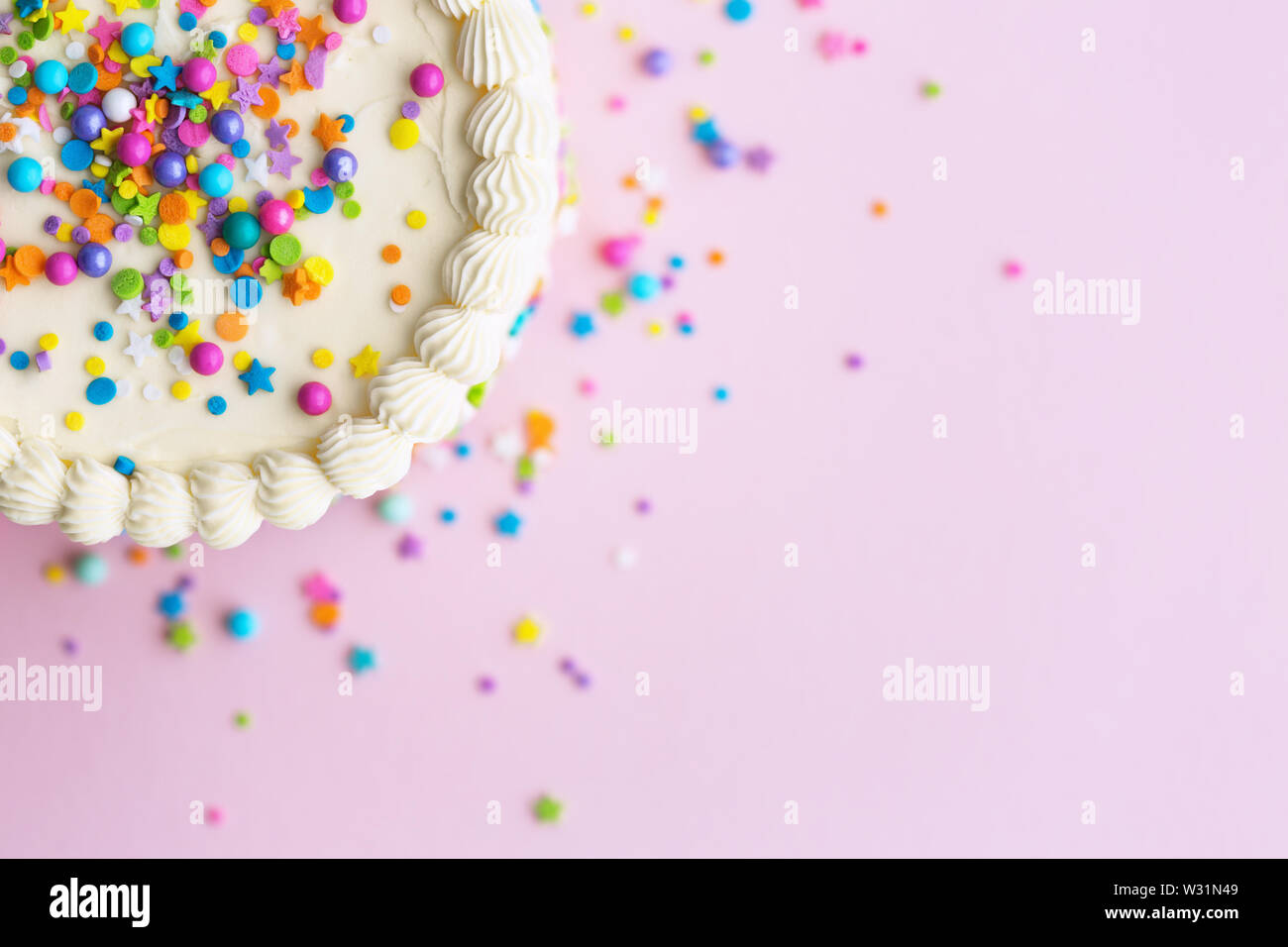 Birthday cake with sprinkles on a pink background Stock Photo