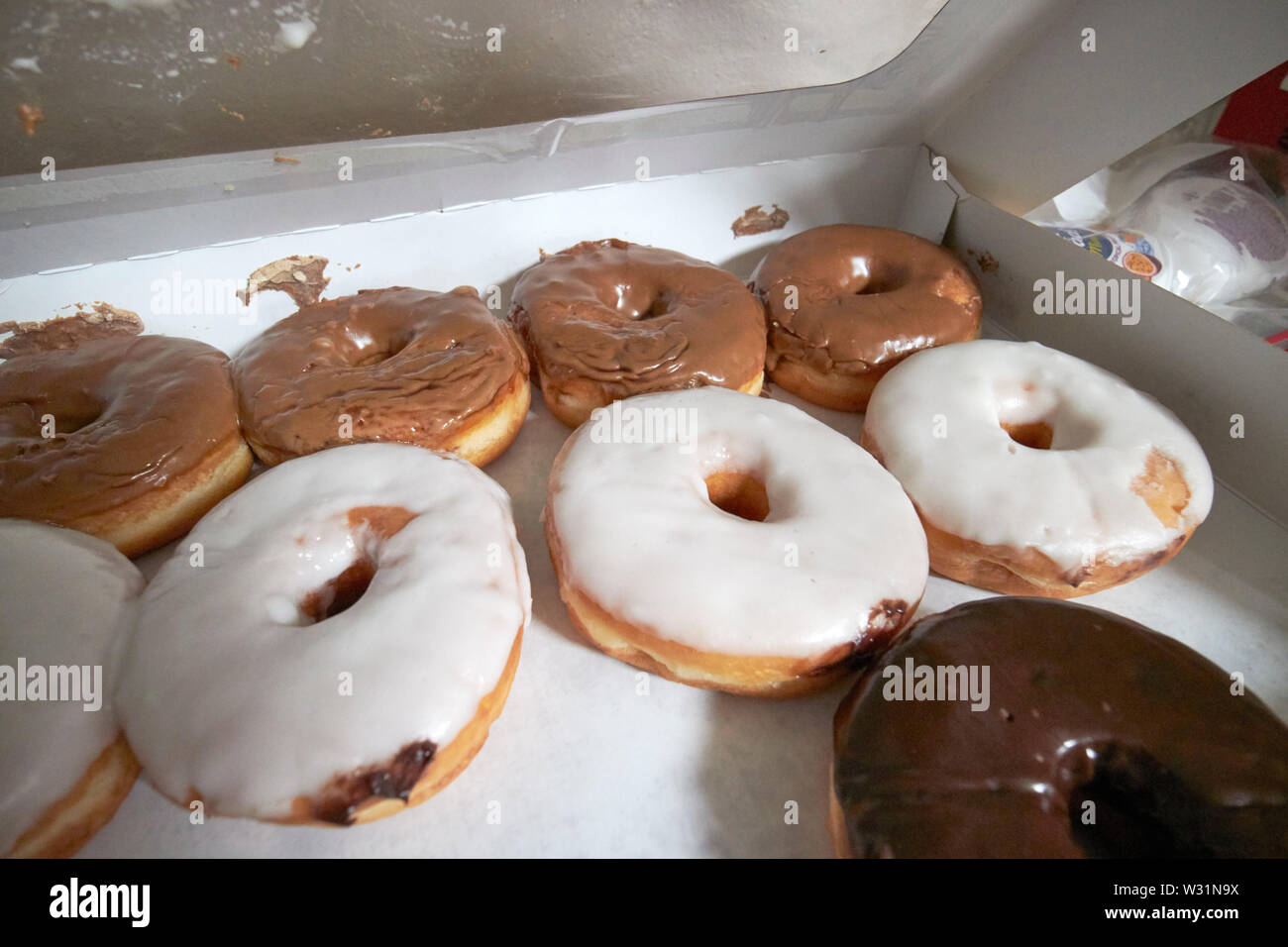 sneaking a peek into a box of iced donuts in the USA United States of America Stock Photo