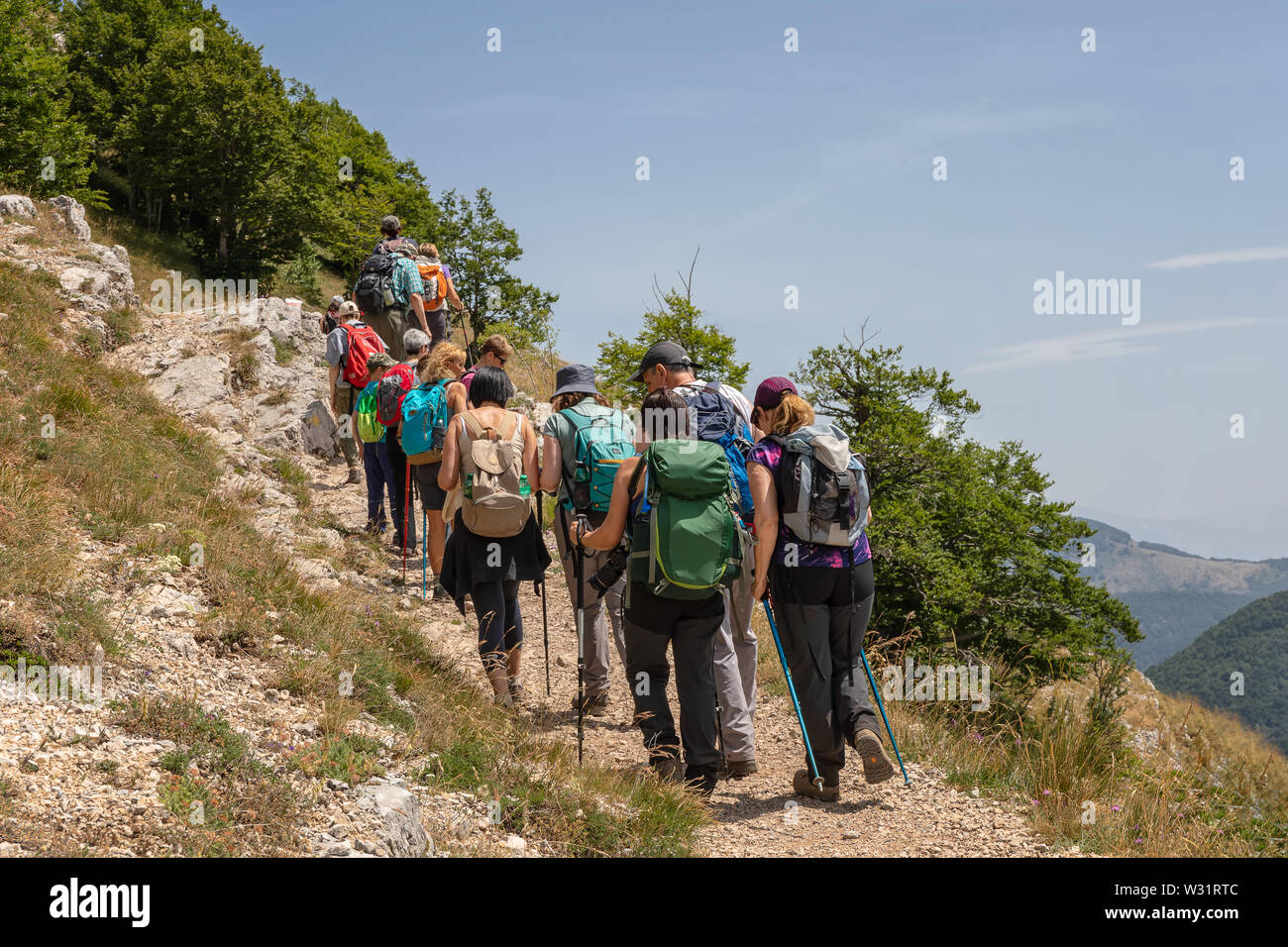 Subiaco RM, Italy - 07 July 2019: Group of hikers on the mountain path, go up the slope of Mount Autore. Stock Photo