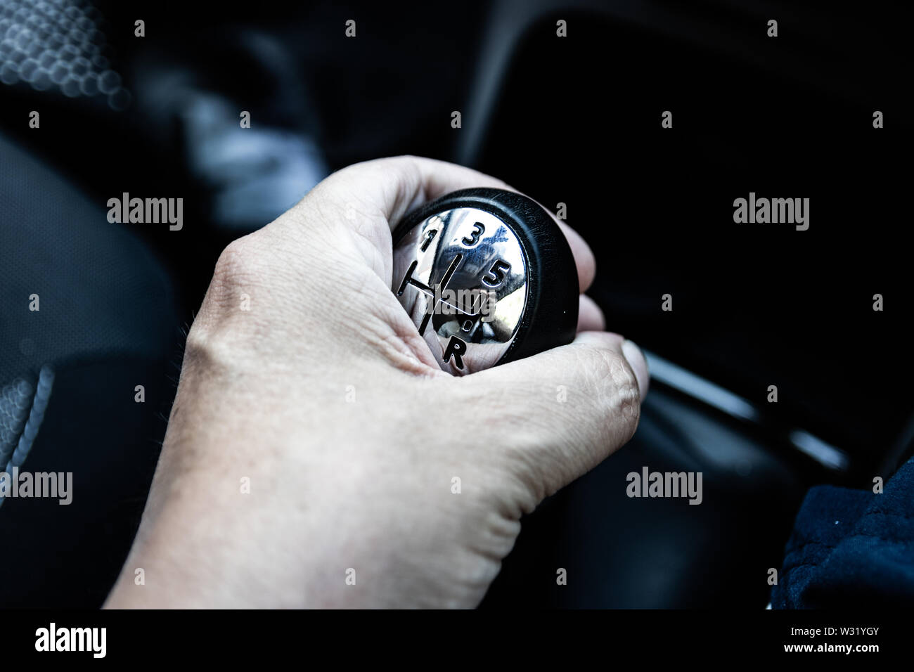 A hand on a car gear stick shifting gears Stock Photo