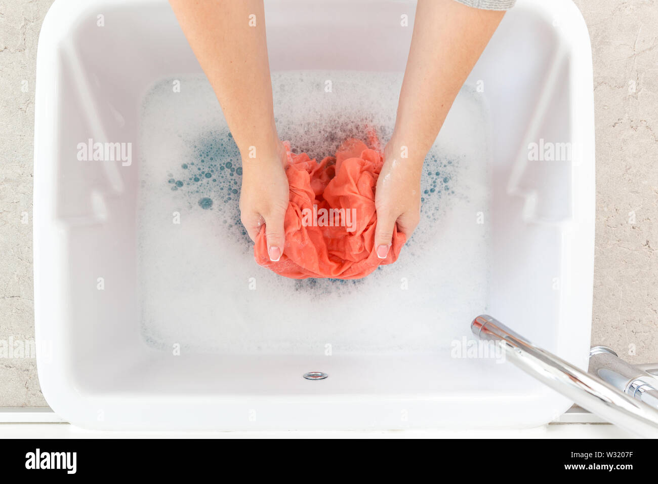 Female Hands Washing Clothes In Sink In Laundry Room Stock