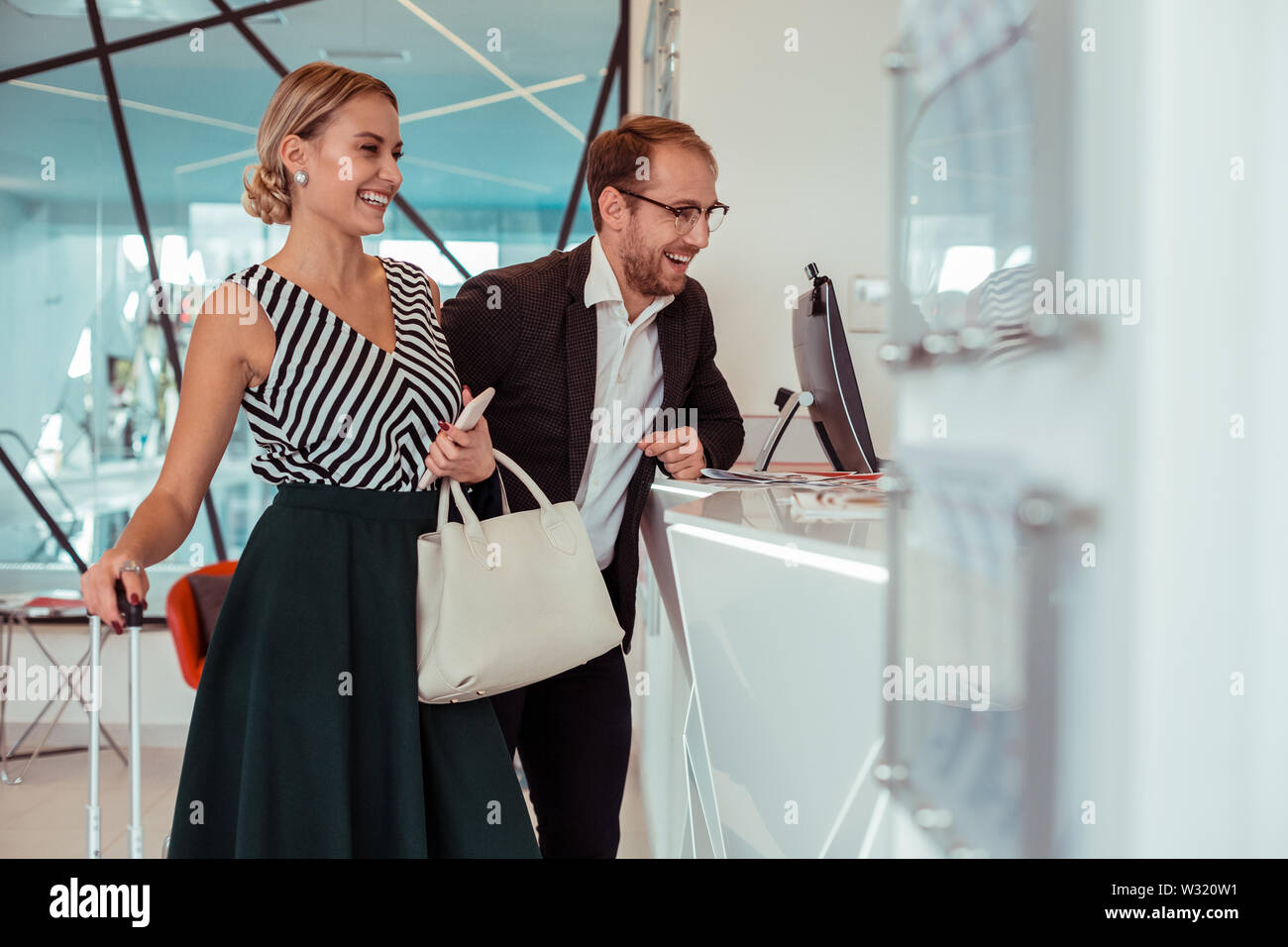 Beaming good-looking couple staying on the reception desk Stock Photo