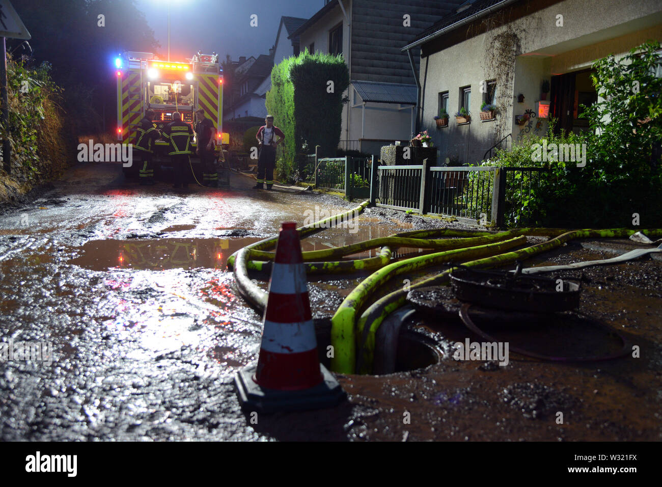 Trier, Germany. 11th July, 2019. Firefighters pump a cellar in the Olewig district empty. A violent storm with heavy rain and hail had swept over the region and flooded numerous streets and cellars. Credit: Harald Tittel/dpa/Alamy Live News Stock Photo