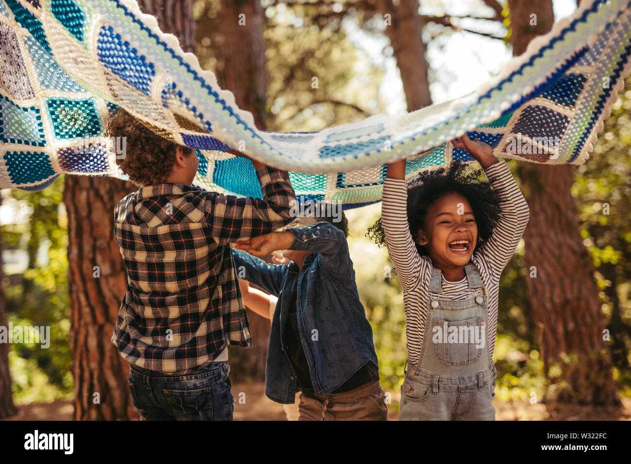 Four kids in park with picnic blanket. Group of children enjoying together in park. Stock Photo