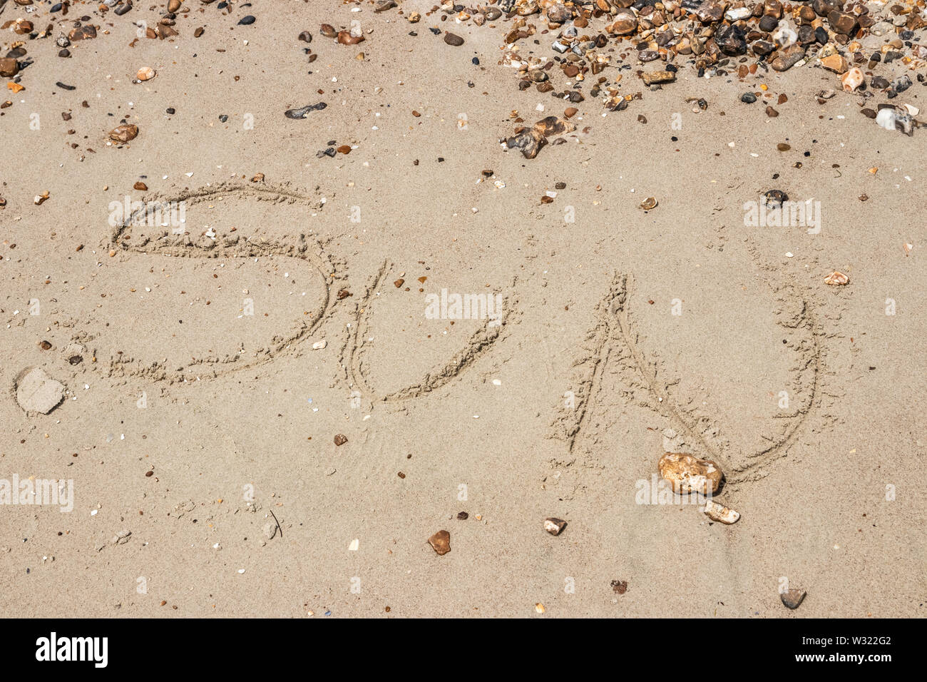 The word sun written in sand on a beach Stock Photo