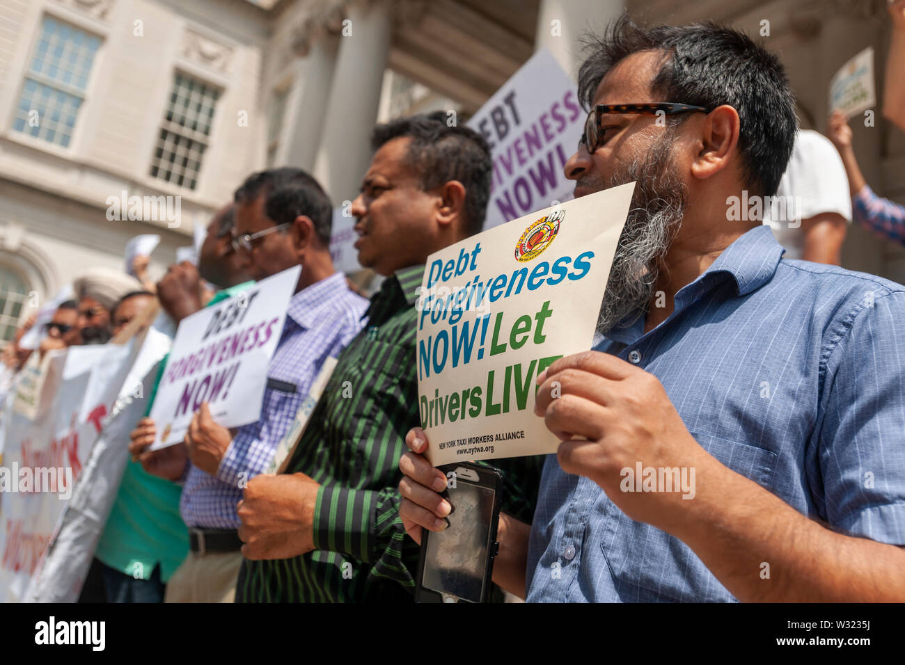 New York taxi drivers and their supporters rally on the steps of NY City Hall in Thursday, July 11, 2019 for a news conference calling for debt forgiveness for their medallion loans. Medallion brokers allegedly took advantage of drivers who bought medallions at artificially inflated prices and ended up burdened with debt. A number of drivers have filed for bankruptcy or are considering it and there have been a few suicides amongst stressed drivers. (© Richard B. Levine) Stock Photo