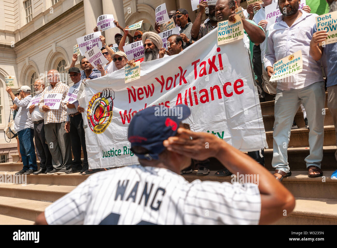 New York taxi drivers and their supporters rally on the steps of NY City Hall in Thursday, July 11, 2019 for a news conference calling for debt forgiveness for their medallion loans. Medallion brokers allegedly took advantage of drivers who bought medallions at artificially inflated prices and ended up burdened with debt. A number of drivers have filed for bankruptcy or are considering it and there have been a few suicides amongst stressed drivers. (© Richard B. Levine) Stock Photo