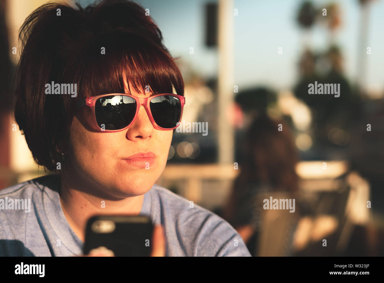 LA, USA - 31ST OCTOBER 2018: Head Portrait of Caucasian female in funky glasses looks down Hollywood Blvd, LA during a bright sunset Stock Photo