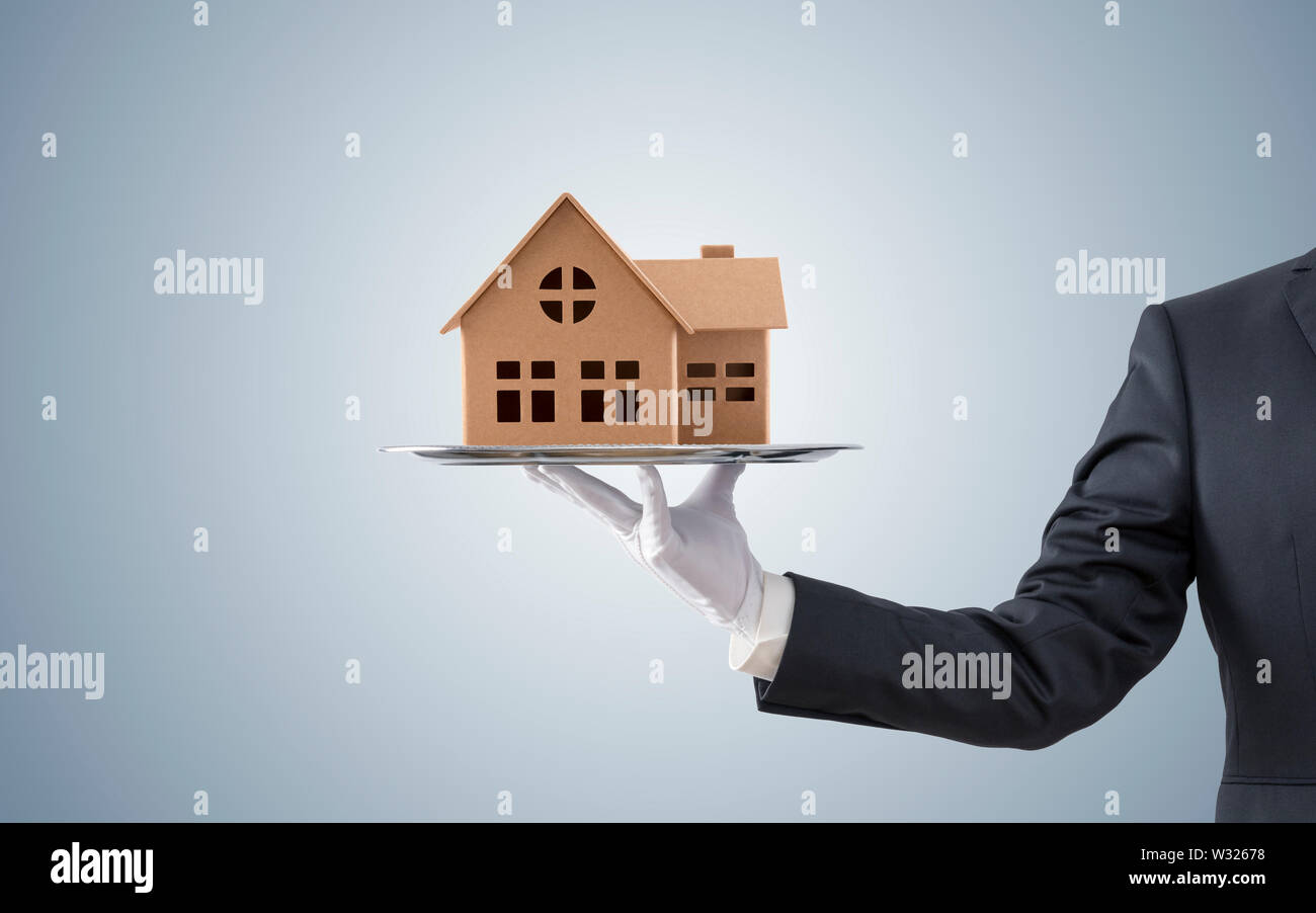 Businessman offering house model on silver tray Stock Photo