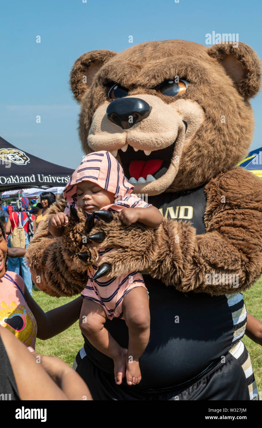 Detroit, Michigan - The bear mascot for Oakland University carries a sleeping baby. Stock Photo