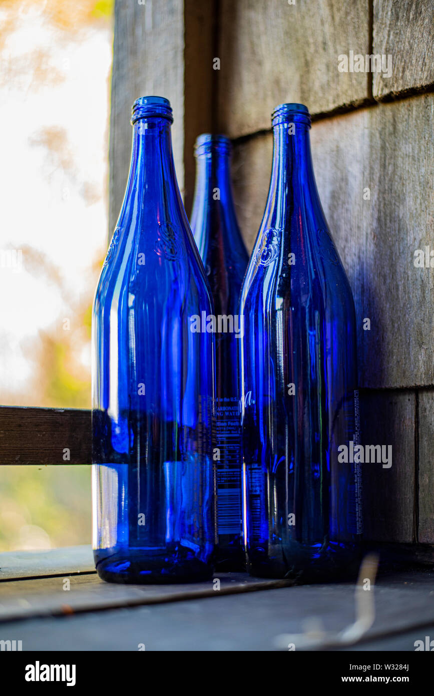 Collection of blue glass wine bottles on a rustic porch Stock Photo Alamy