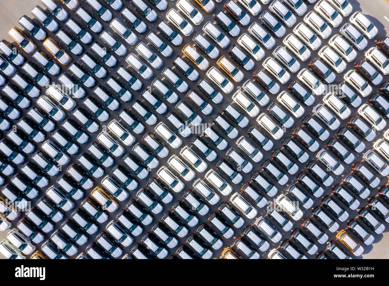 Aerial top view new cars lined up in the port for import export business logistic and transportation by ship in the open sea. New cars from the car fa Stock Photo