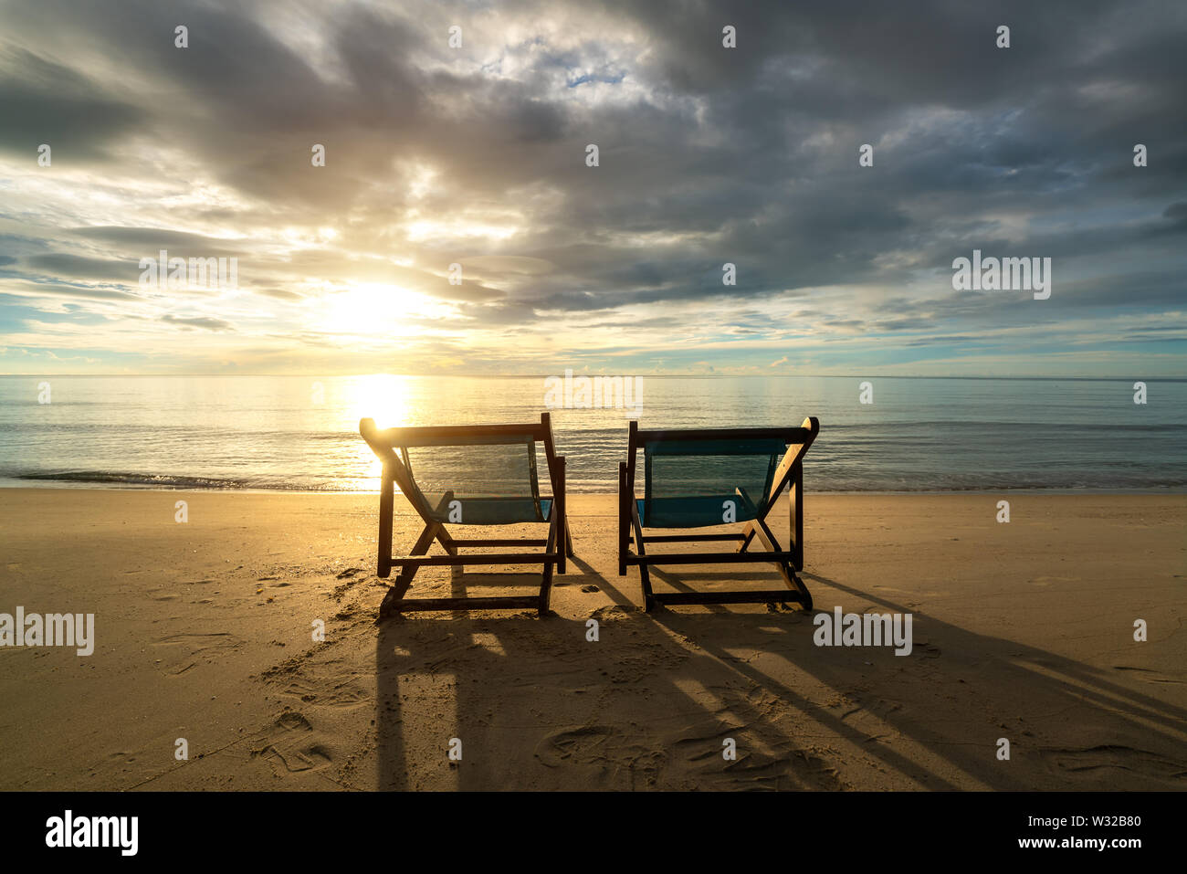 Two deckchairs on the beach at sunset with a tropical sea background. Travel and Vacation in Summer at sea. Stock Photo