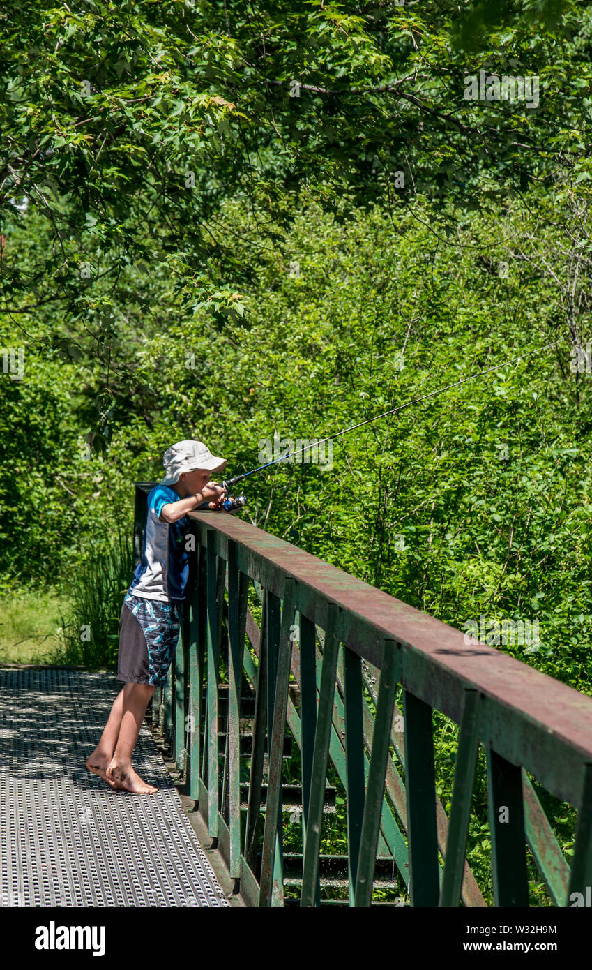 young boy fishing from a bridge Stock Photo
