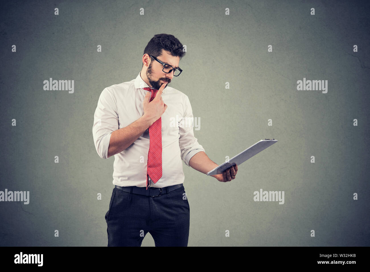 Thoughtful business man touching chin and using tablet computer Stock Photo
