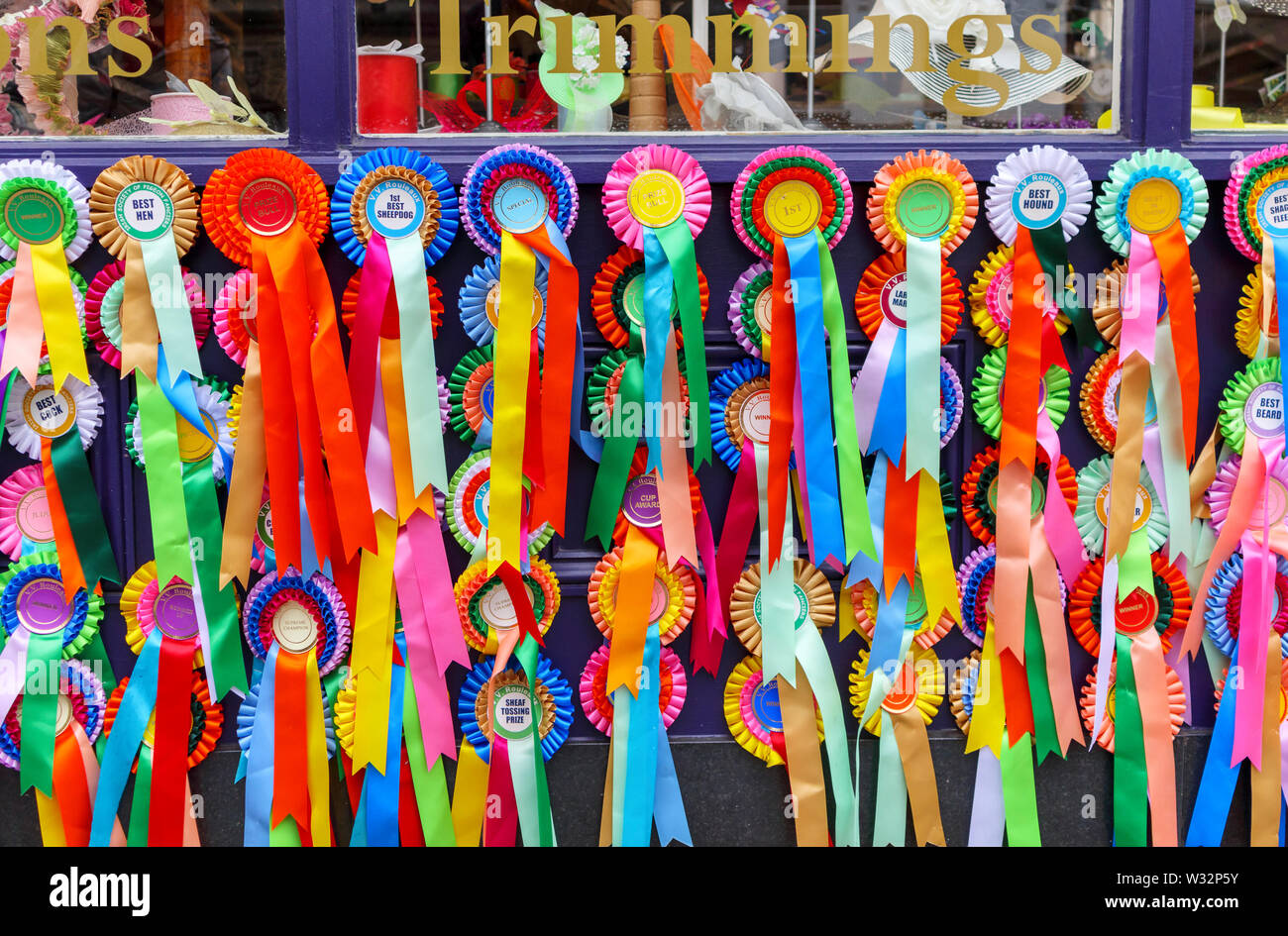 Brightly coloured prize and award rosettes and ribbons on display outside a shop in Bath, the largest city in Somerset, south-west England, UK Stock Photo