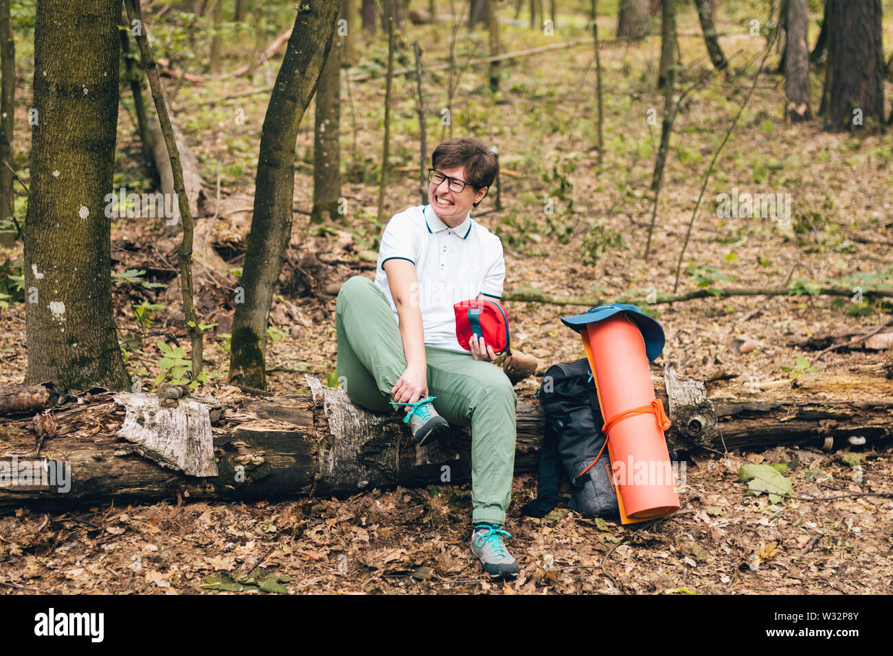 Young woman having trouble feeling knee pain during travel in forest ...