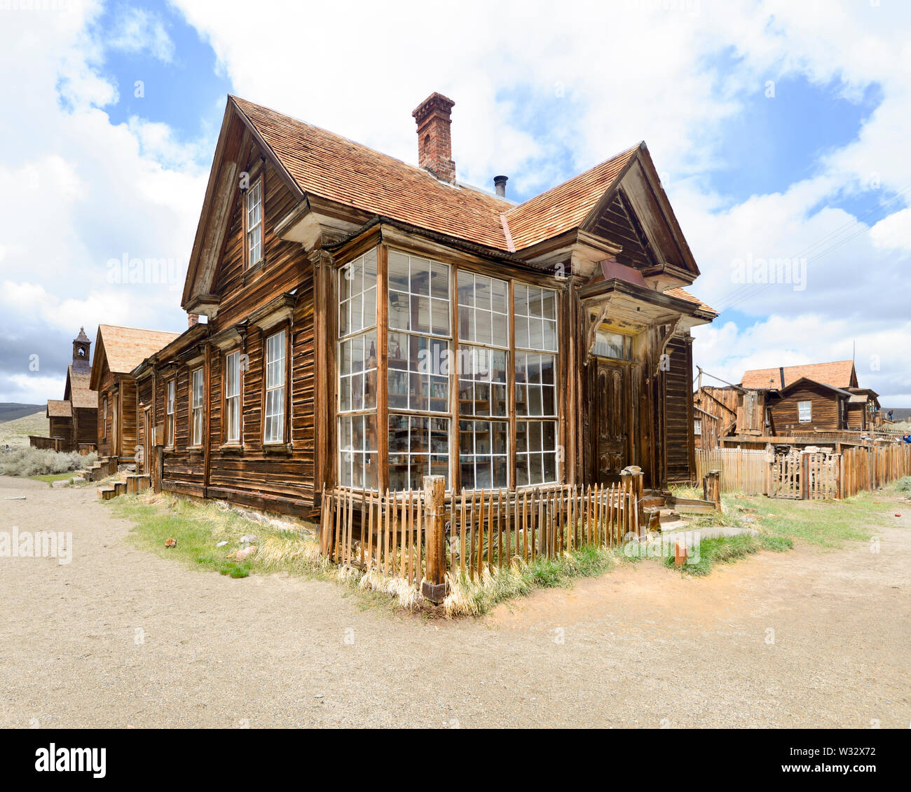 Bodie,Sierra Nevada, California, gold rush Ghost Town, House with antique bottles visible through large windows, picket fence, blue sky, white clouds Stock Photo