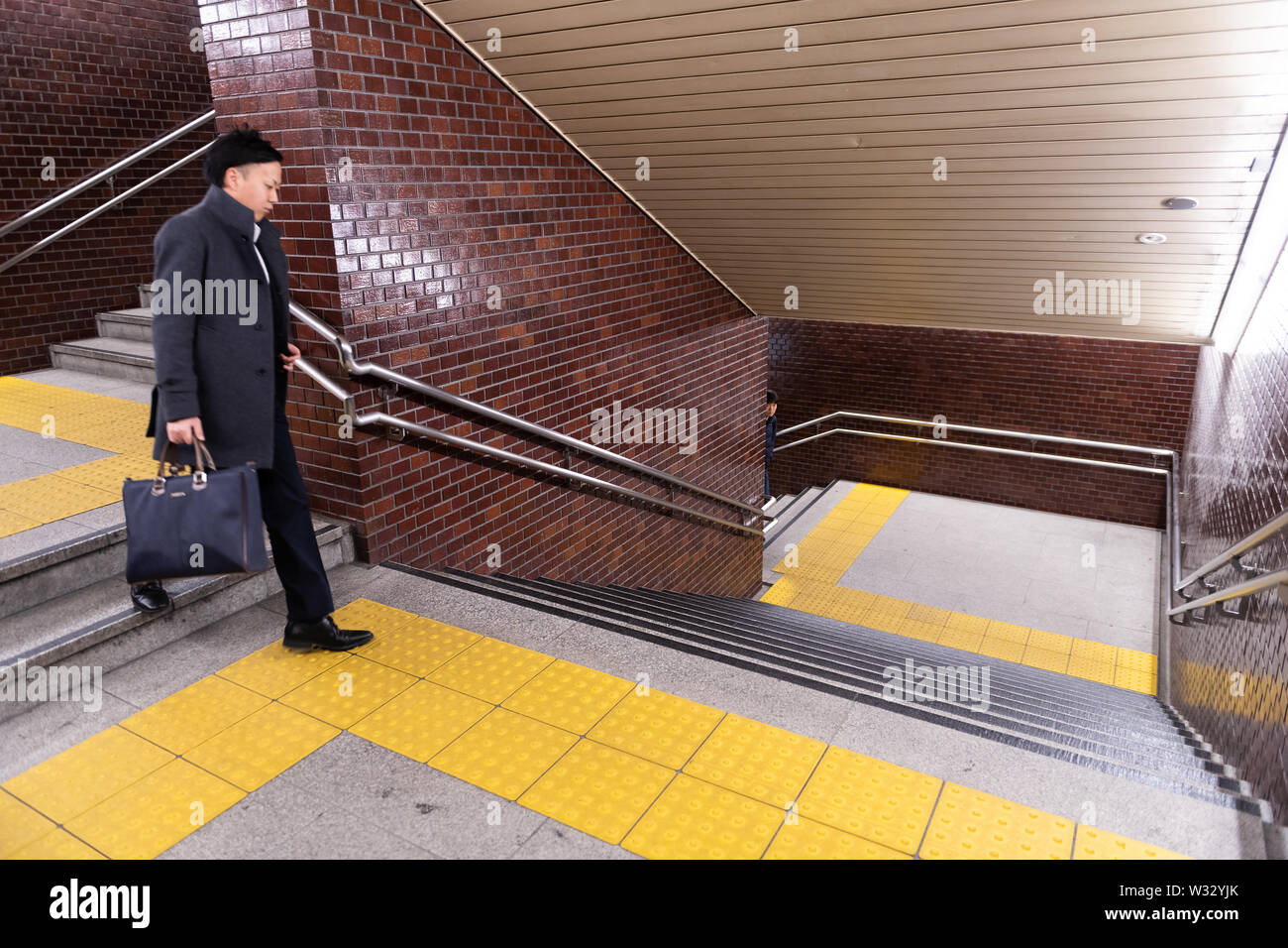 Tokyo, Japan - April 4, 2019: Underground staircase stairs or steps with Japanese businessman with metal railing in Shinjuku train station Stock Photo