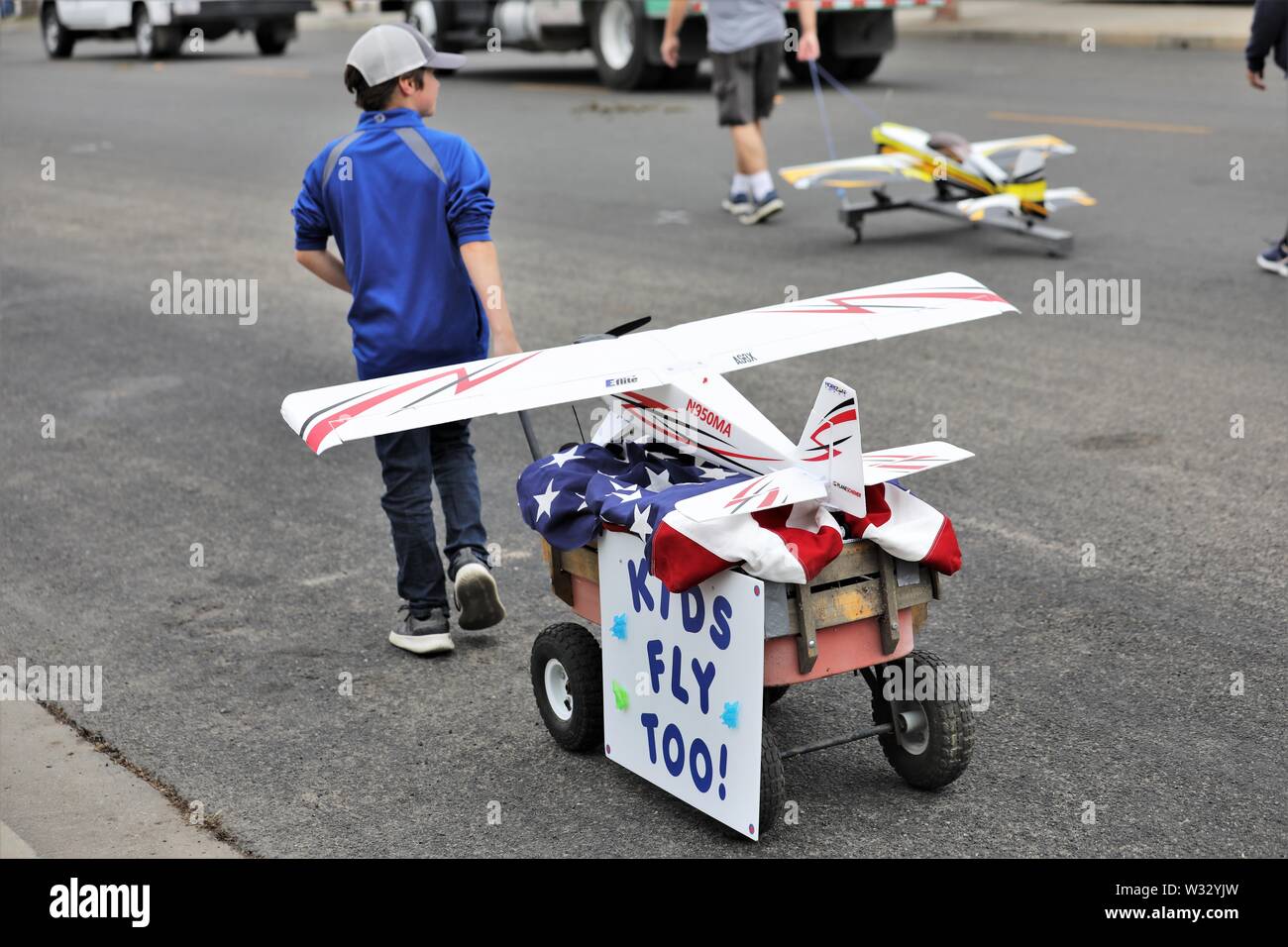 Young boy with his remote control airplane  who is marching in real parade to show kids do the flying also, not just adults like his father dad Stock Photo
