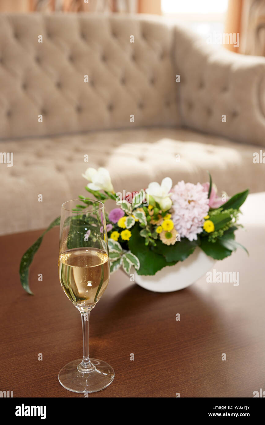 Bouquet and glass of champagne on table in hotel lobby Stock Photo