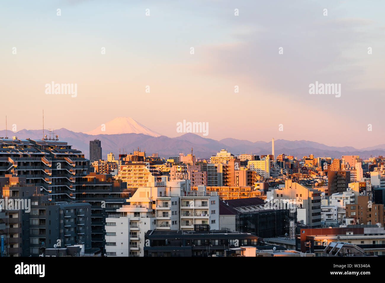 Colorful sunset in Tokyo, Japan Shinjuku cityscape with silhouette of Mount Fuji and golden sunlight, apartment buildings and mountains Stock Photo
