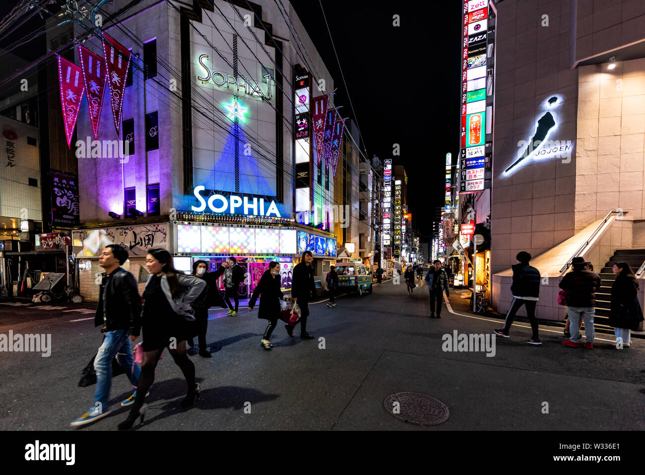Shinjuku, Japan - April 4, 2019: People walking on narrow alley lane street of Kabukicho by restaurants, izakaya and adult entertainment club at night Stock Photo