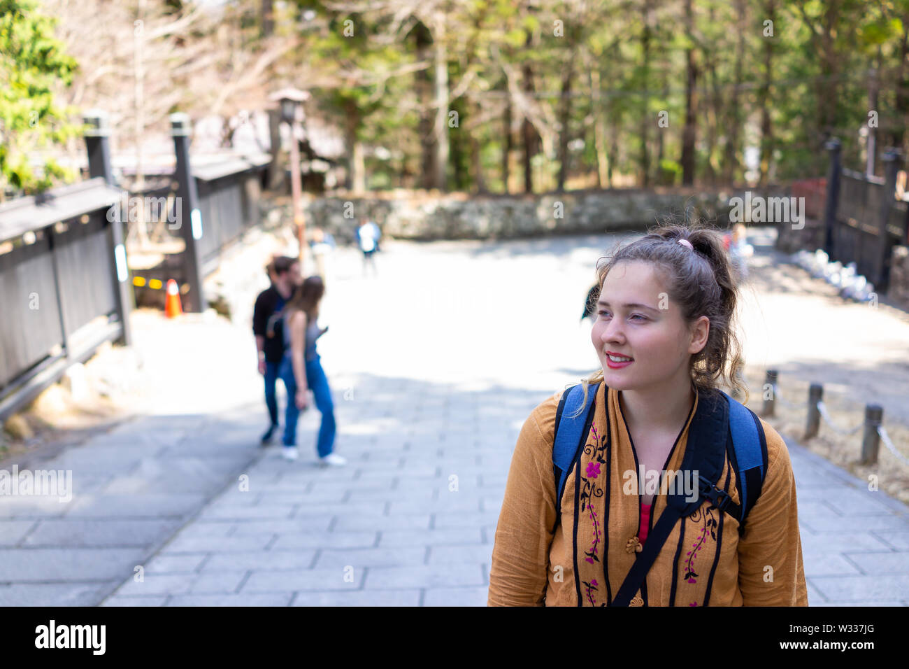 Young smiling happy woman, caucasian foreigner traveler walking in Nikko, Japan on street road by forest in spring Stock Photo
