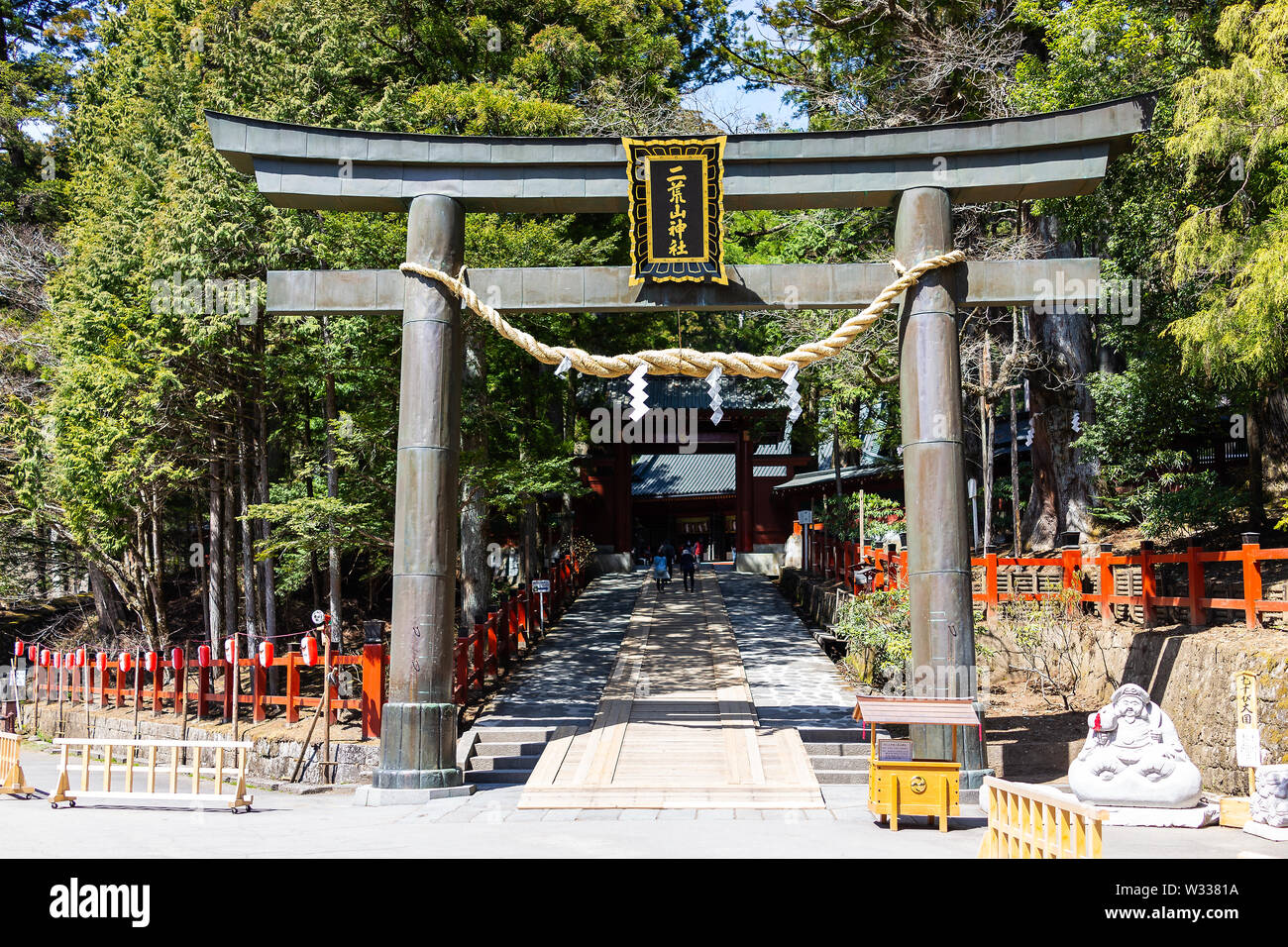 Nikko, Japan - April 4, 2019: People walking by entrance to Futarasan temple shrine with torii gate, rope and paper in Tochigi prefecture in spring Stock Photo