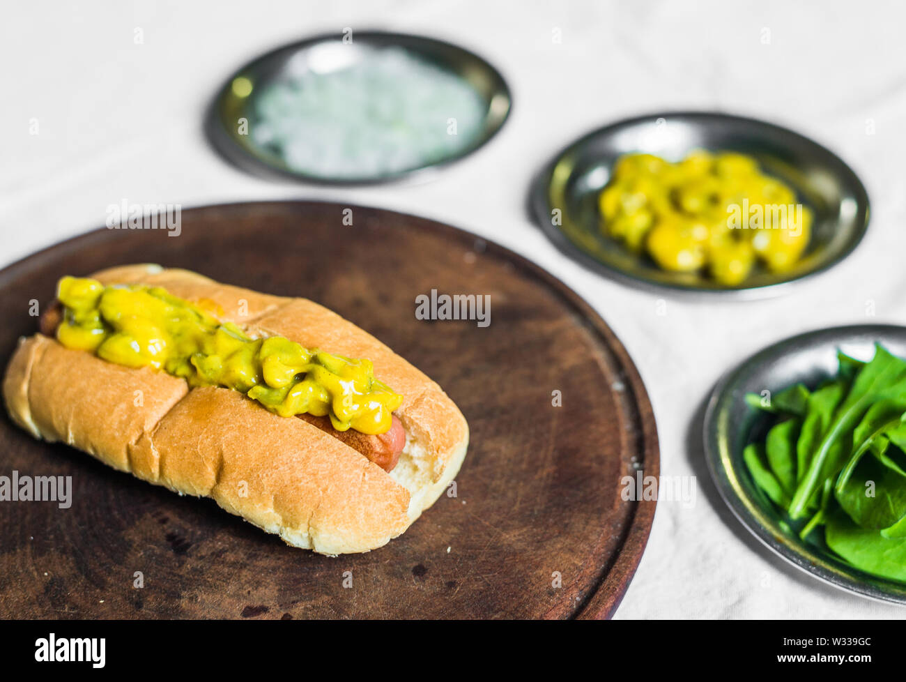 Traditional hot dog with gherkin and mustard relish against white