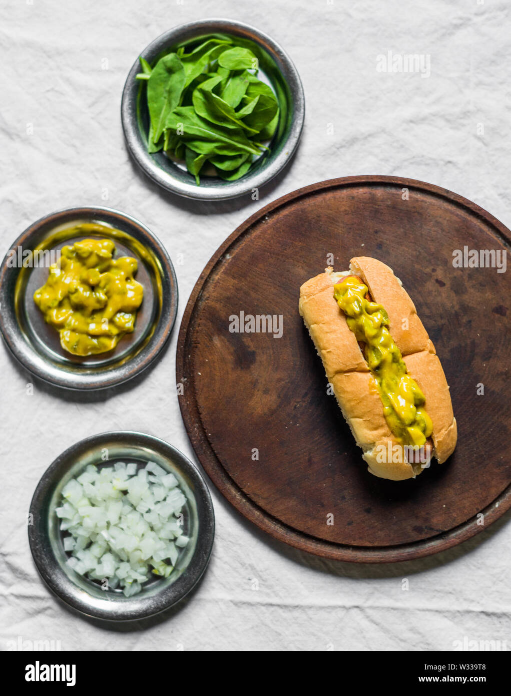Traditional hot dog with gherkin and mustard relish against white