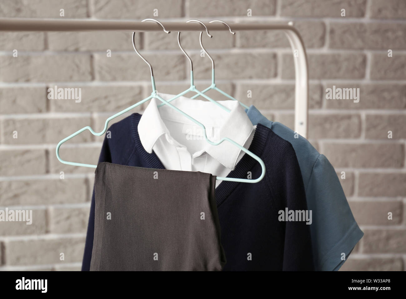 Stylish school uniform hanging on rack against brick wall Stock Photo ...