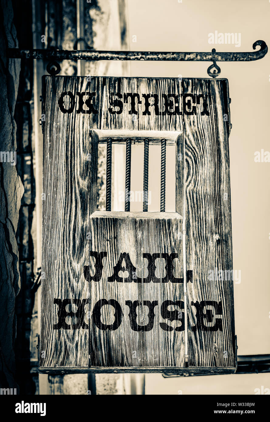 A handmade wooden sign hangs overhead the entrance to the OK Street Jailhouse, now a B and B in historic Bisbee, AZ, USA, in sepia Stock Photo