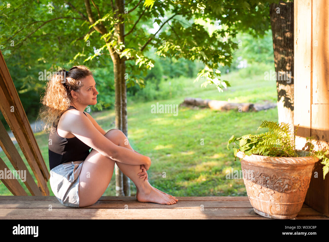Spring house porch with happy woman sitting on steps of house in front ...