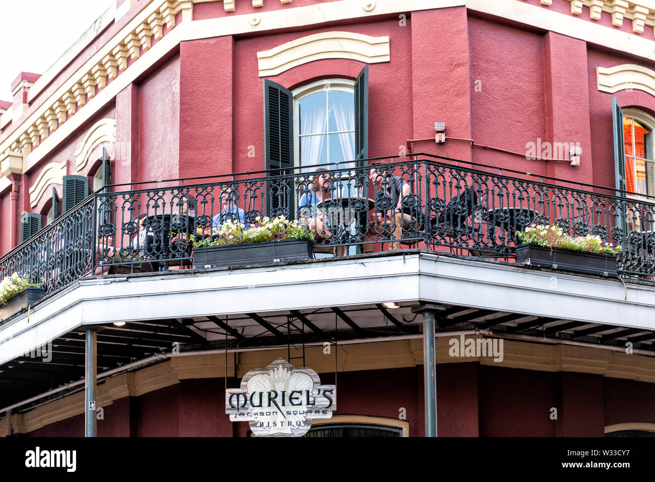 New Orleans, USA - April 22, 2018: People couple sitting at Muriel's Jackson square bistro restaurant at cast iron wrought building balcony in Louisia Stock Photo
