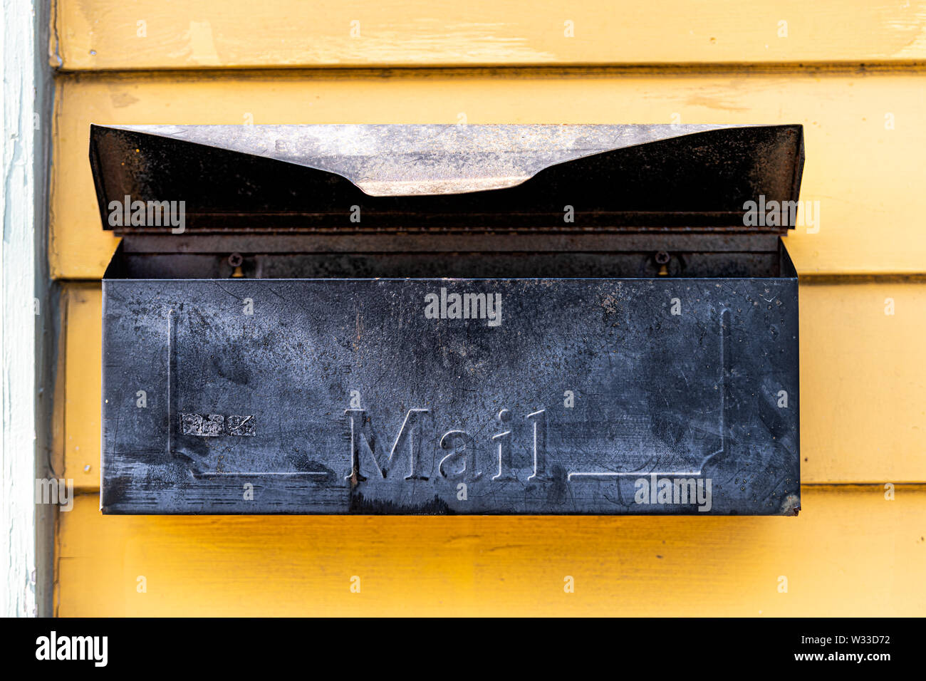 Old retro vintage door mail box, mailbox attached to house home wall exterior painted in yellow color in New Orleans, Louisiana Stock Photo