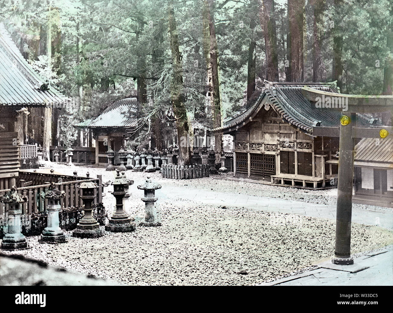 [ 1890s Japan - Sacred Shrines at Nikko ] —   The 6 meter high Karado Torii, the first bronze torii in Japan, as seen from the Yomeimon in Nikko. The building in the center is Shinkyu, the stable for sacred horses and the only building of plain wood in Toshogu Shrine. The entrance gate on the left is Niomon.  19th century vintage glass slide. Stock Photo