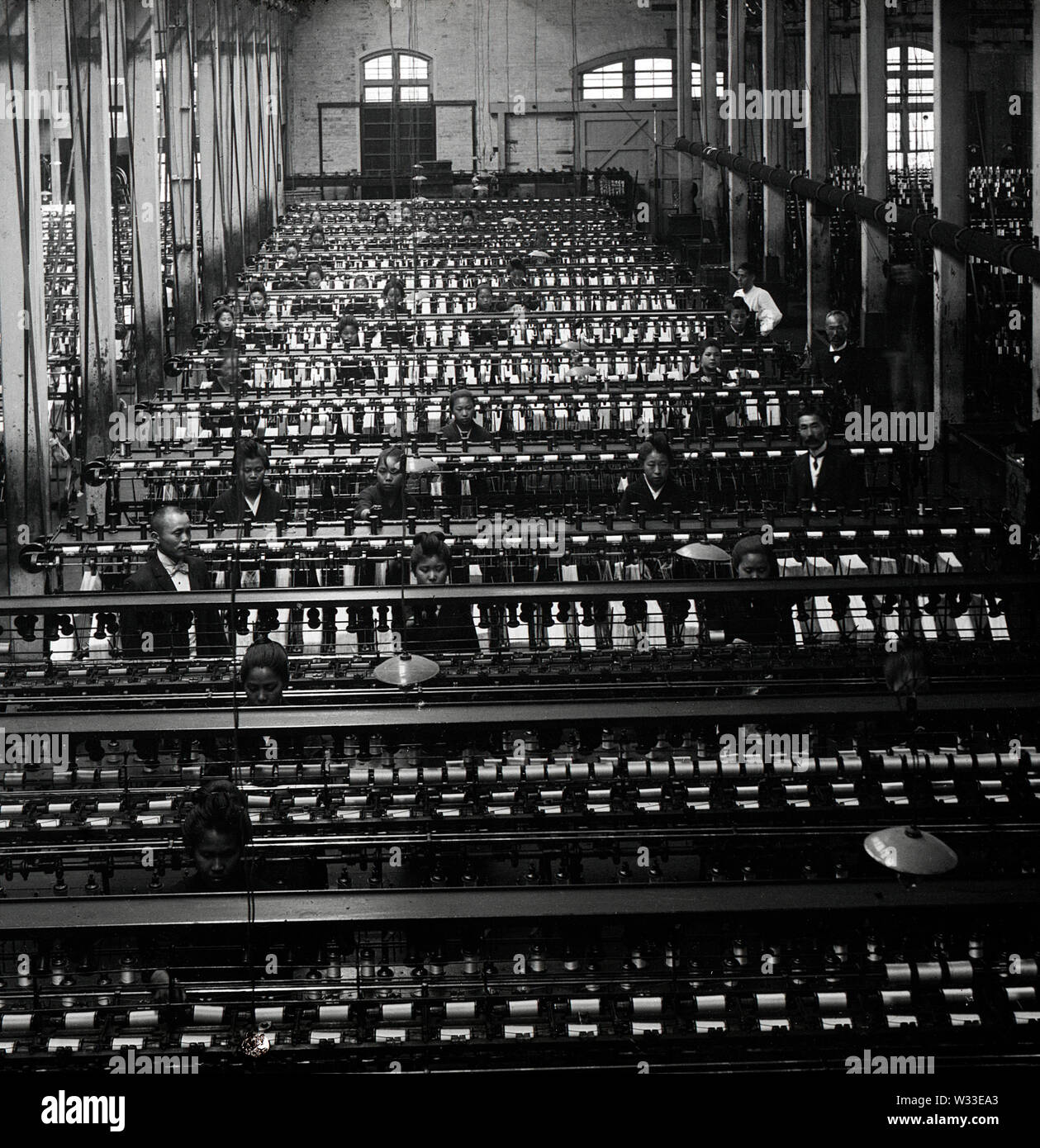 [ 1900s Japan - Japanese Silk Factory ] —   The spindle room at the Kiryu Orimono KK (Kiryu Textile Company Ltd.), a Japanese silk factory in Kiryu, Gunma Prefecture. The company was launched as the Nihon Orimono KK (Japan Textile Company, Ltd.) in 1887 (Meiji 20). At the time it was Japan's largest and most modern silk factory where the complete production process was done by machinery.  20th century vintage glass slide. Stock Photo