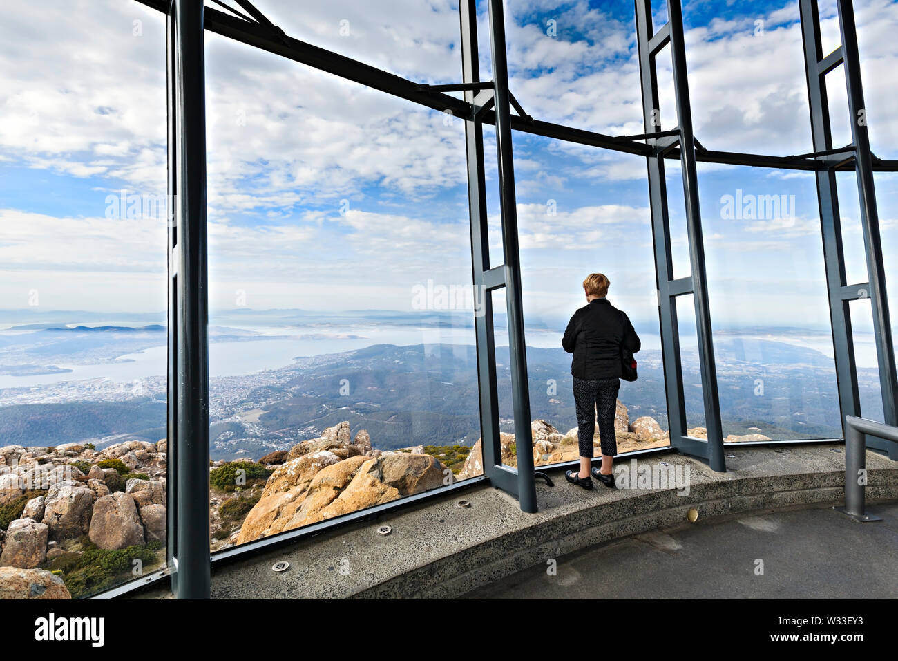 Hobart Australia / A lone female tourist enjoys the spectacular view over Hobart from the summit of Mount Wellington. Stock Photo