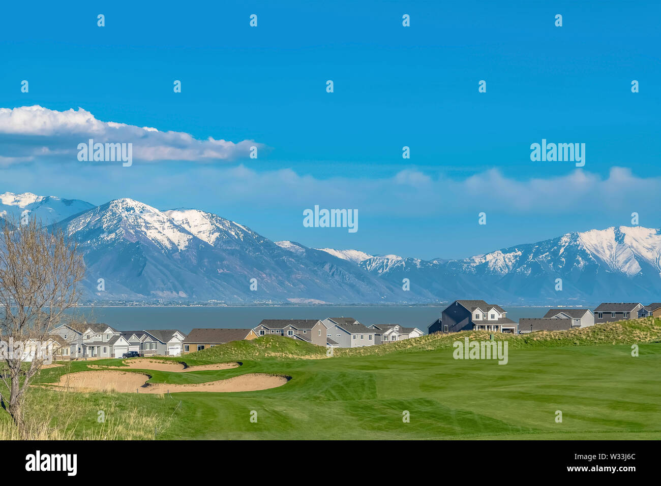 Houses on a grassy hill with scenic view of a lake and blue sky with