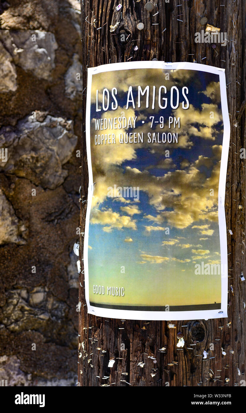 A photo of a cloudscape advertisement poster for the band, 'Los Amigos',  posted on a wooden light pole with hundreds of remaining staples and tacks Stock Photo