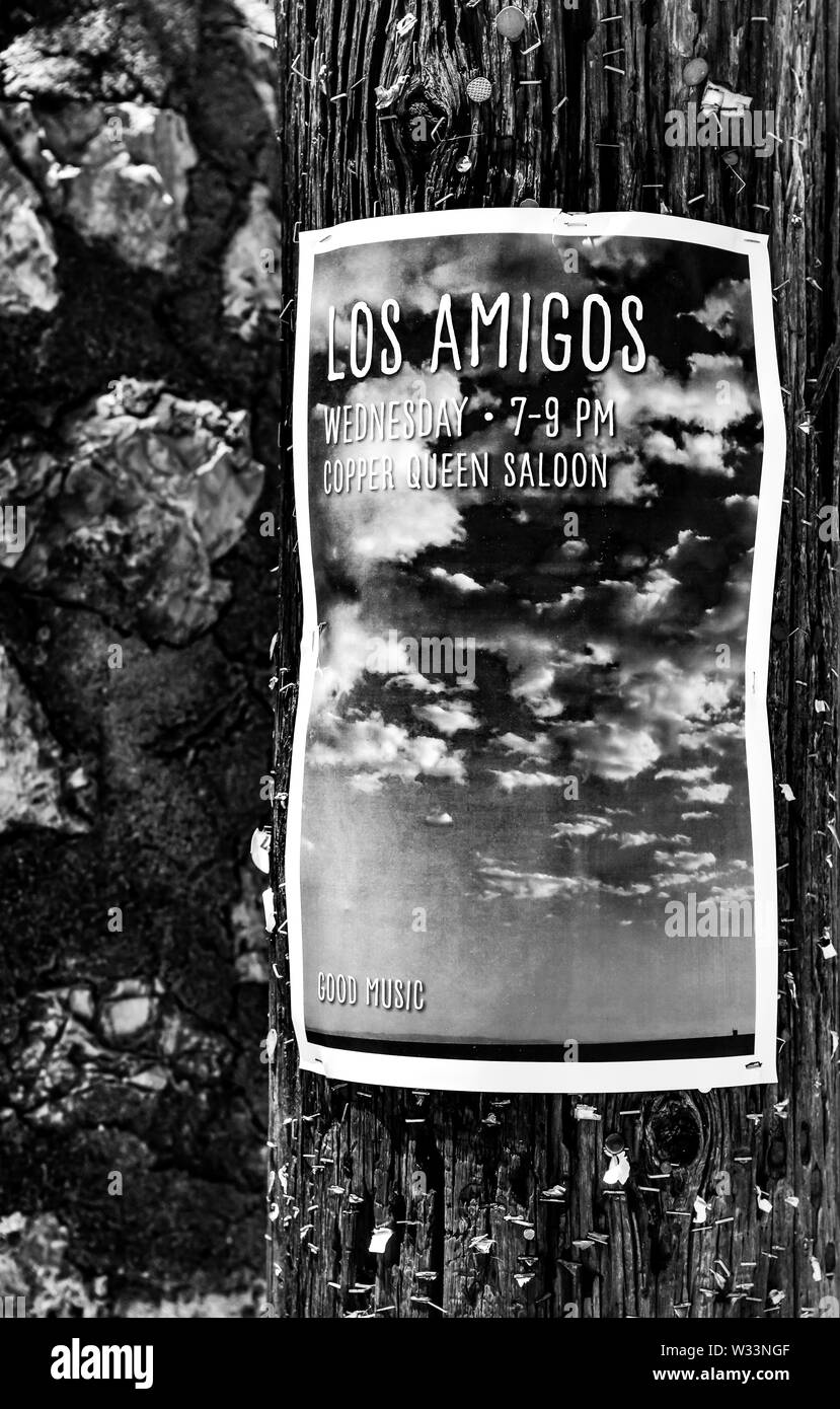 A photo of a cloudscape advertisement poster for the band, 'Los Amigos',  posted on a wooden light pole with hundreds of remaining staples and tacks Stock Photo