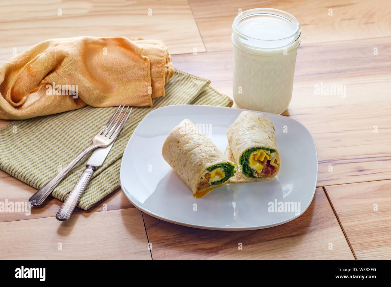 Egg and bacon American breakfast sandwich wrap with a glass of milk ...