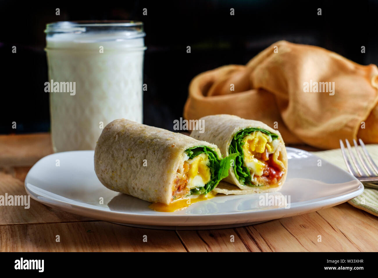 Egg and bacon American breakfast sandwich wrap with a glass of milk ...