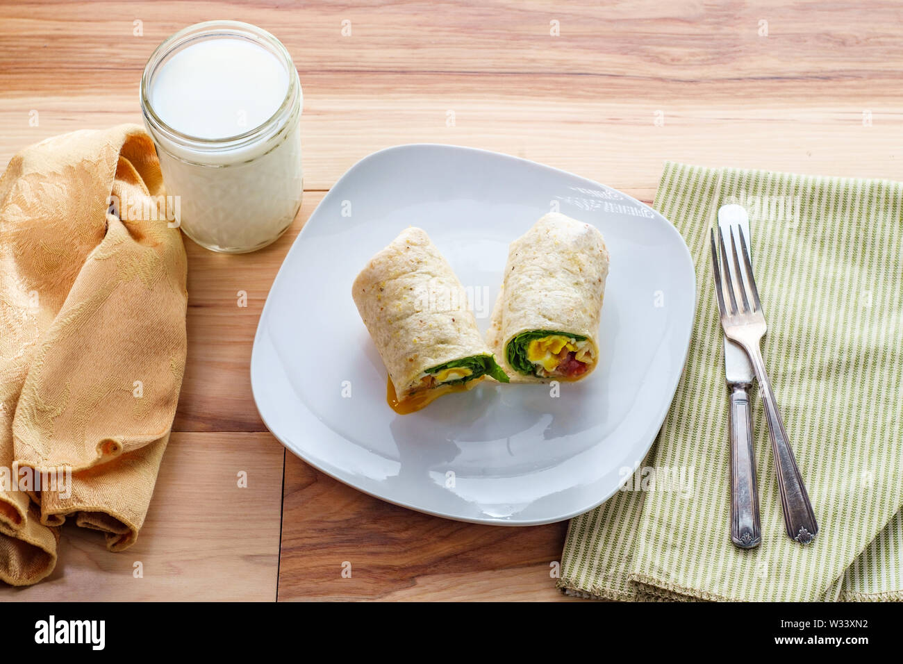 Egg and bacon American breakfast sandwich wrap with a glass of milk ...