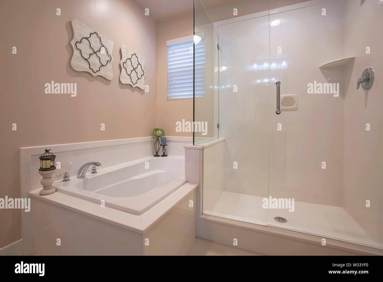 Bathroom Interior With A Polished Built In Bathtub And Shower Stall.  Candles, Wall Decorations, And Window With Blinds Can Also Be Seen Inside  The Roo Stock Photo - Alamy