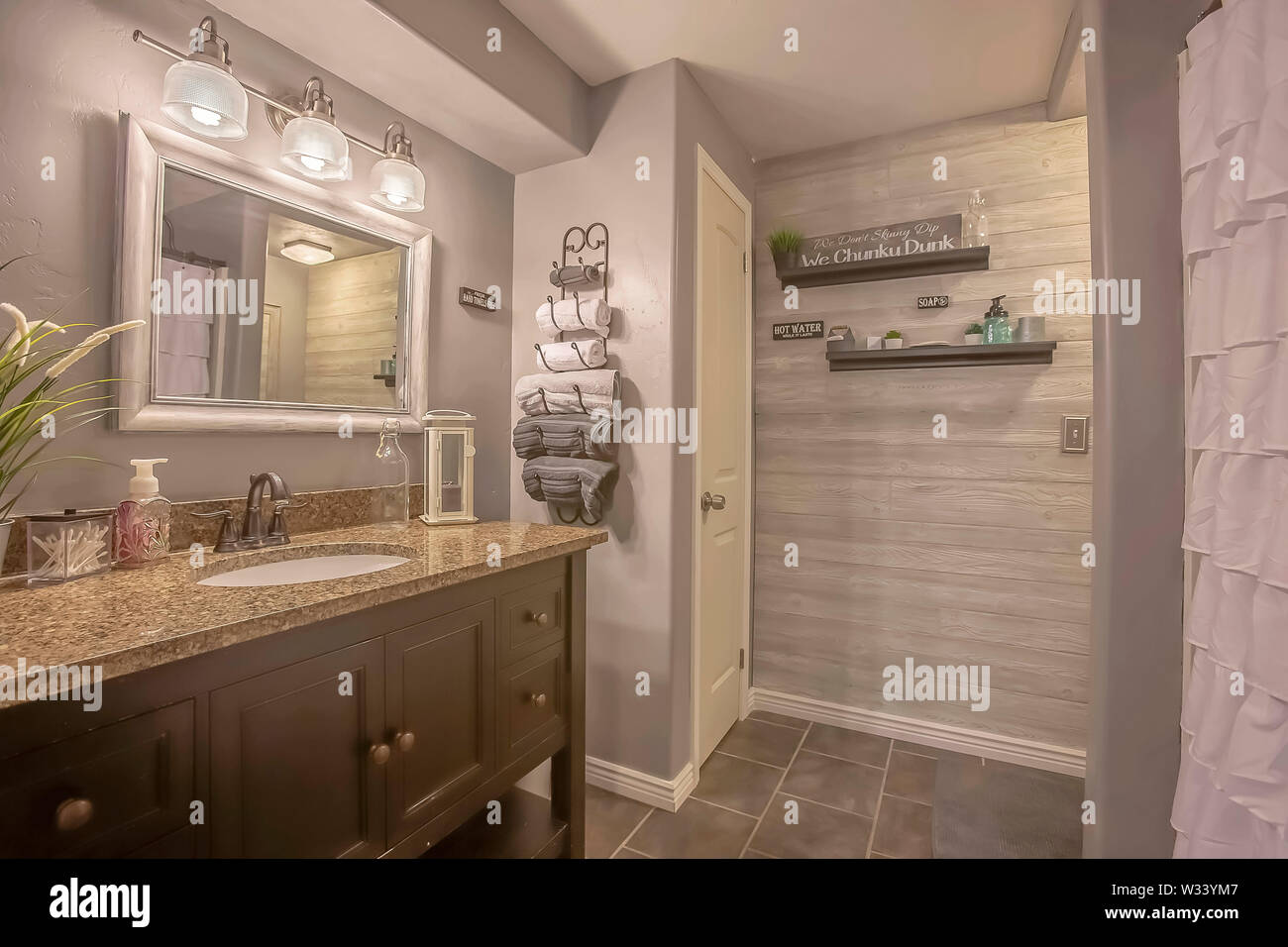 Mirror And Lamps Above The Vanity Inside A Bathroom With Towel Rack And Shelves A White Curtain Conceals The Bathtub And Shower Area Stock Photo Alamy