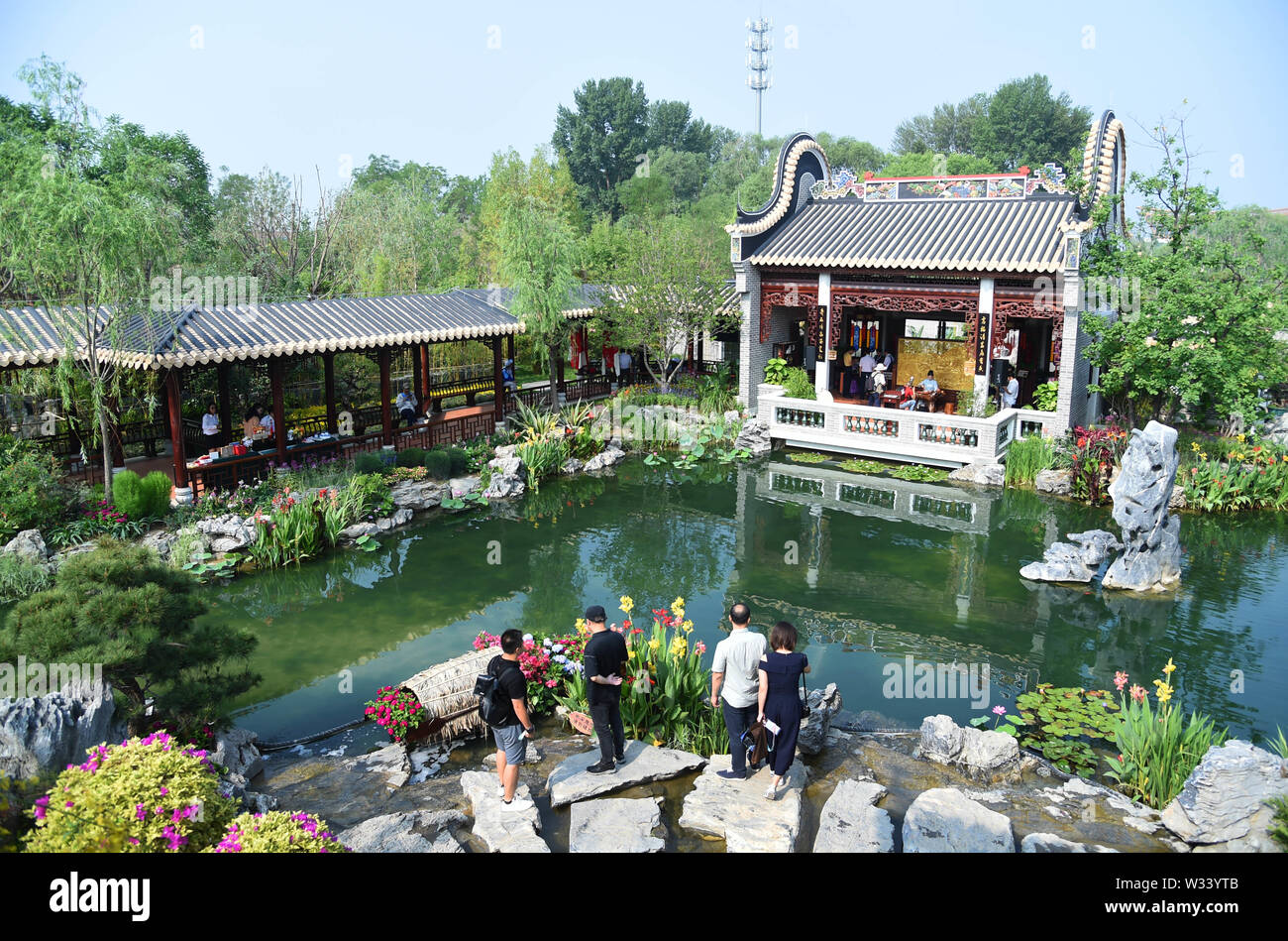 (190712) -- BEIJING, July 12, 2019 (Xinhua) -- Tourists visit the 'Nanyue Garden' during the 'Guangdong Day' event at the Beijing International Horticultural Exhibition in Beijing, capital of China, July 11, 2019. Located in south China, Guangdong Province faces the South China Sea and borders Hunan and Jiangxi provinces to the north. It boasts the well-known Pearl River Delta, which is composed of three upstream rivers and a large number of islands. Due to the climate, Guangdong is famous for a diversified ecological system and environment. In recent years, by upholding the principle of gr Stock Photo
