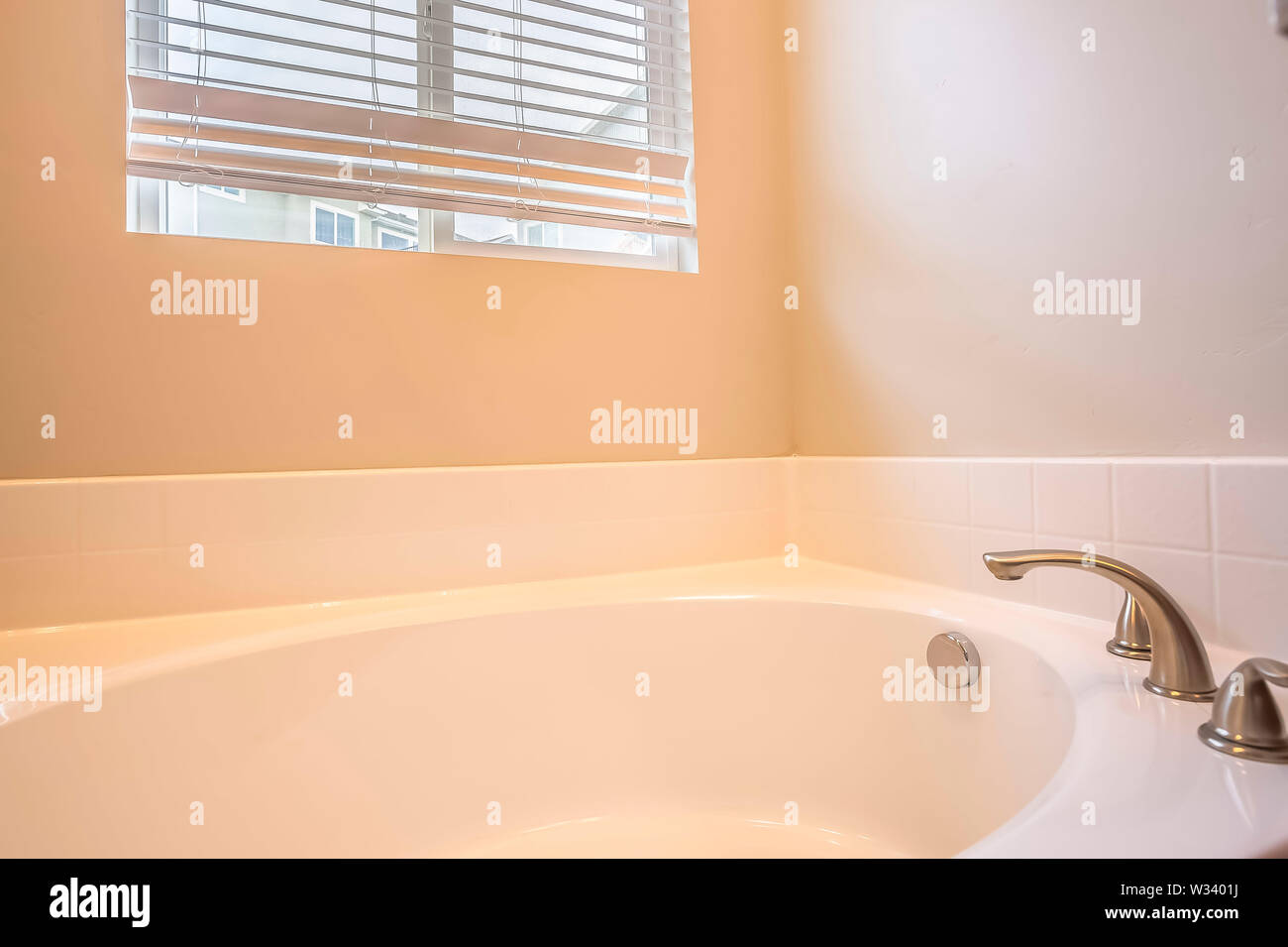 Bathroom interior with gleaming white oval bathtub and stainless steel ...