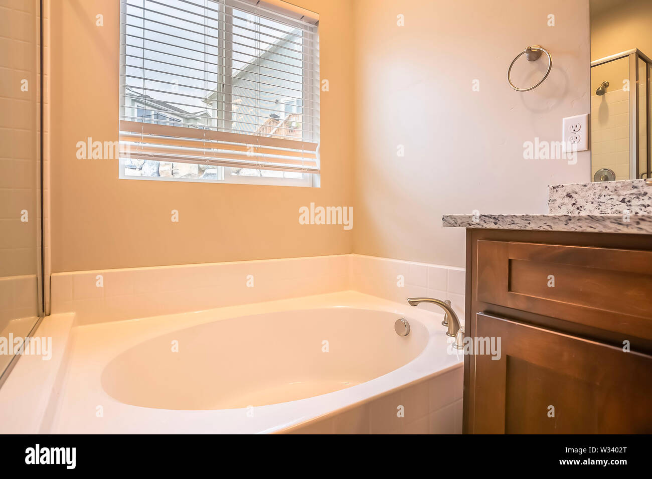 Bathroom interior with oval bathtub against white wall and window with